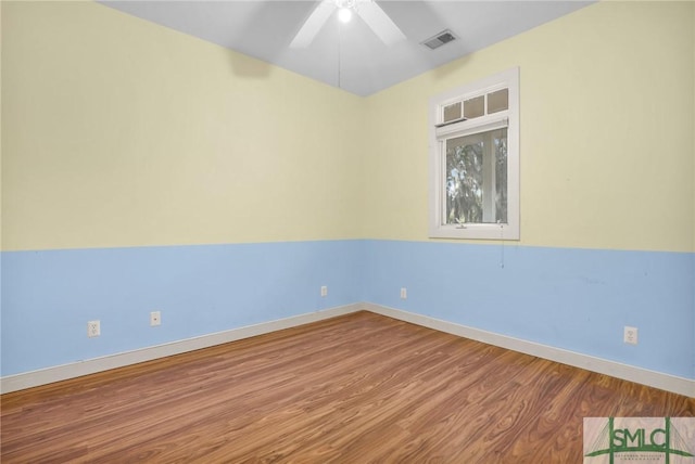 spare room with baseboards, ceiling fan, visible vents, and wood finished floors
