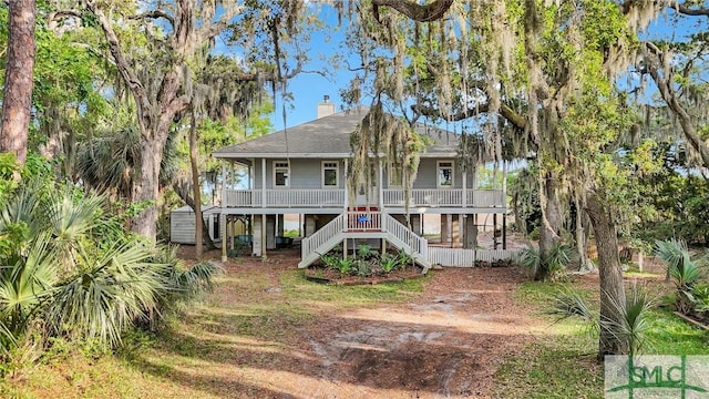 back of property featuring a porch, a chimney, stairs, and roof with shingles