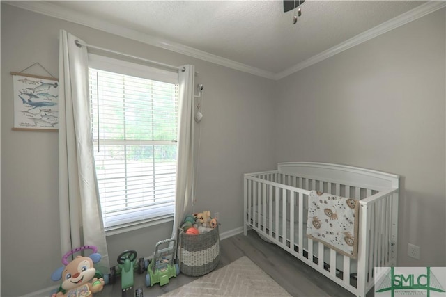 bedroom featuring a crib, ornamental molding, multiple windows, and wood finished floors