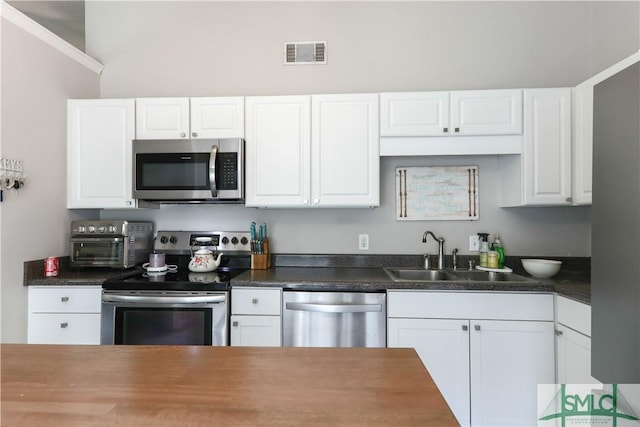 kitchen with visible vents, a sink, a toaster, white cabinets, and stainless steel appliances