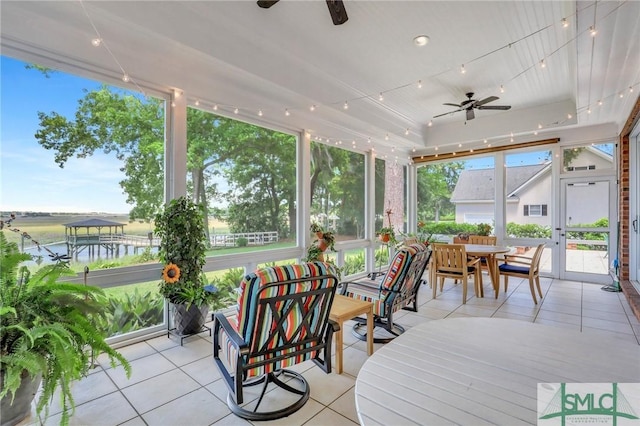 sunroom with tile patterned flooring, a ceiling fan, and outdoor dining area