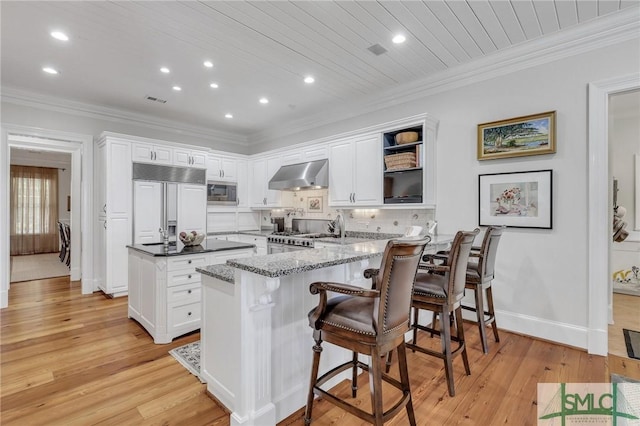kitchen with exhaust hood, built in appliances, a center island, recessed lighting, and a peninsula