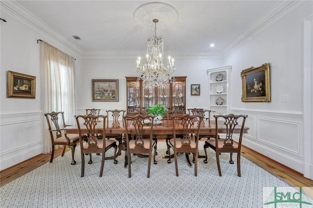 dining space with crown molding, built in shelves, and light wood finished floors