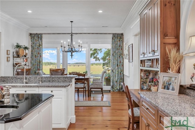 kitchen featuring a sink, ornamental molding, light wood finished floors, and a notable chandelier