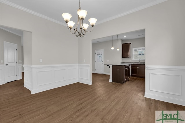 interior space featuring a notable chandelier, a sink, ornamental molding, a wainscoted wall, and dark wood-style floors