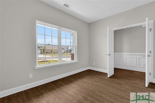 spare room with baseboards, visible vents, and wood finished floors