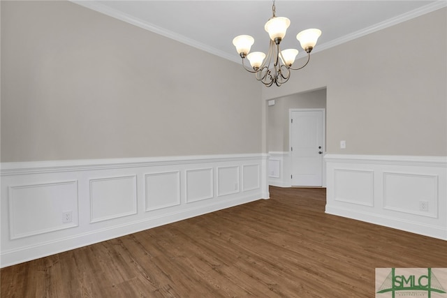 unfurnished dining area featuring ornamental molding, wainscoting, wood finished floors, and a notable chandelier