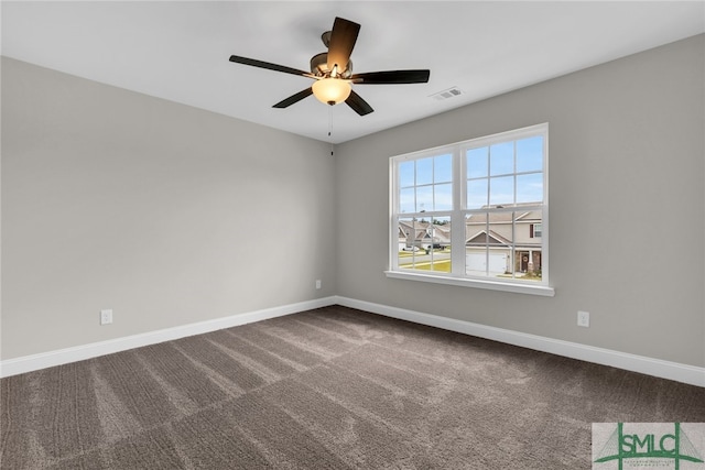 unfurnished room with baseboards, a ceiling fan, dark carpet, and visible vents