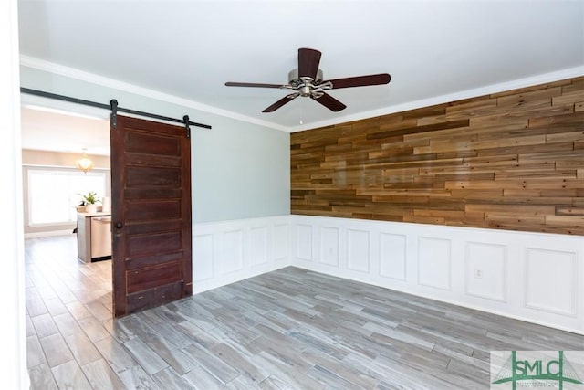 204 Archibald St, Rincon, GA 31326 - empty room with a barn door, ceiling fan, light wood-style floors, ornamental molding, and a wainscoted wall
