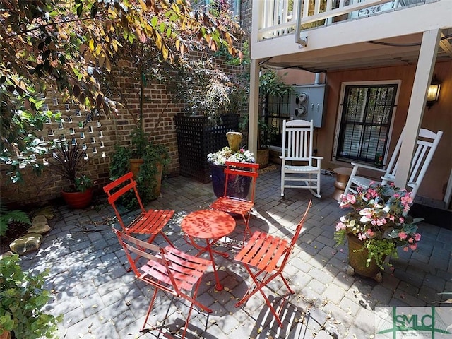 view of patio with fence, outdoor dining area, and a balcony