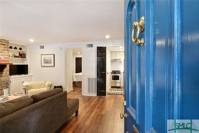 living room featuring recessed lighting, dark wood-style flooring, and visible vents