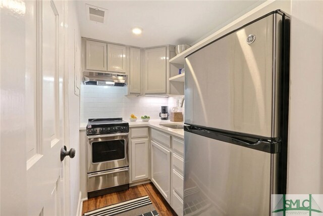 kitchen featuring visible vents, appliances with stainless steel finishes, light countertops, dark wood-style floors, and under cabinet range hood
