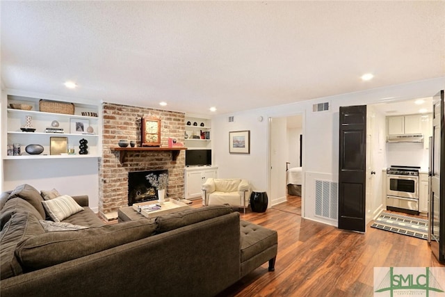 living area with built in features, a fireplace, dark wood-style flooring, and visible vents