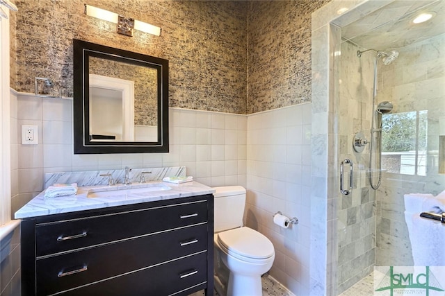 bathroom featuring vanity, tile walls, a shower stall, and toilet