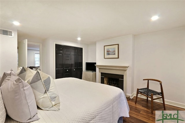bedroom featuring visible vents, baseboards, wood finished floors, and a fireplace