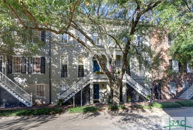 view of front facade with stairway, a porch, and stucco siding