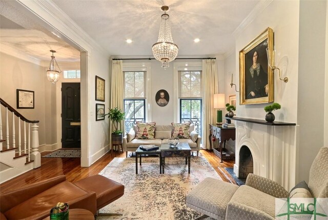 living room with ornamental molding, wood finished floors, baseboards, stairway, and a chandelier
