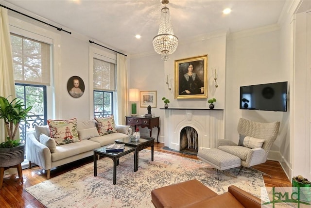 living room featuring ornamental molding, a fireplace, a chandelier, and hardwood / wood-style flooring