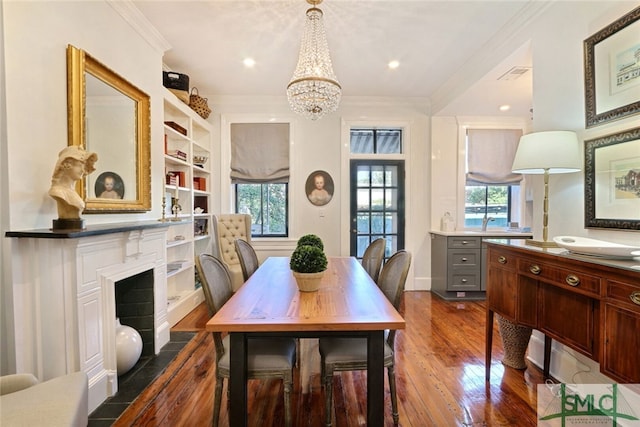 dining space with plenty of natural light, crown molding, dark wood-type flooring, and a chandelier