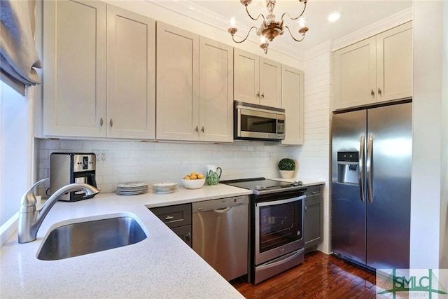kitchen featuring a notable chandelier, a sink, dark wood finished floors, stainless steel appliances, and decorative backsplash