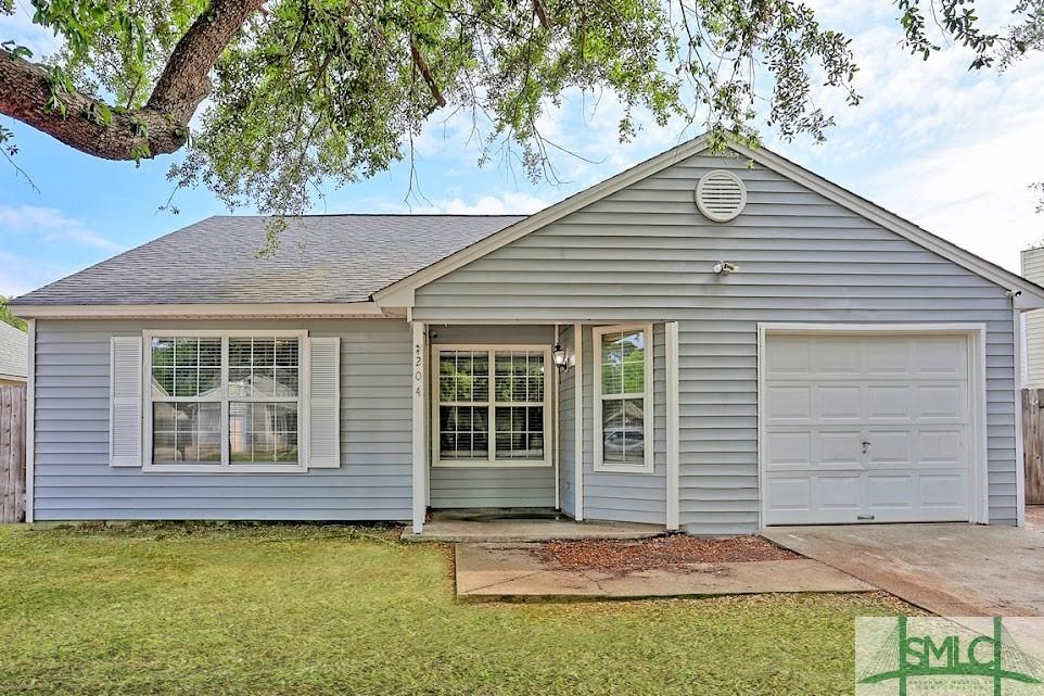 view of front of property with roof with shingles, an attached garage, driveway, and a front yard