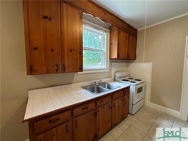 724 E 49th St, Savannah, GA 31405 - kitchen with brown cabinets, white range with electric stovetop, a sink, tile countertops, and baseboards