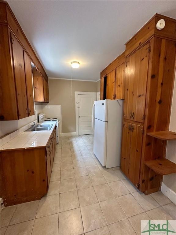 724 E 49th St, Savannah, GA 31405 - kitchen featuring brown cabinetry, freestanding refrigerator, baseboards, tile counters, and a sink