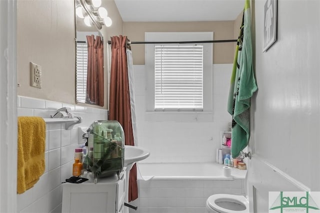 724 E 49th St, Savannah, GA 31405 - bathroom with vanity, toilet, a wainscoted wall, tiled shower / bath, and tile walls