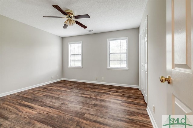 spare room featuring a ceiling fan, a textured ceiling, visible vents, dark wood finished floors, and baseboards