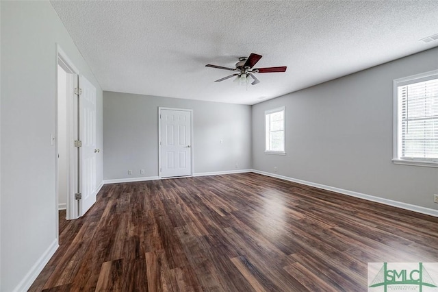 empty room with baseboards, ceiling fan, dark wood-style flooring, and a textured ceiling