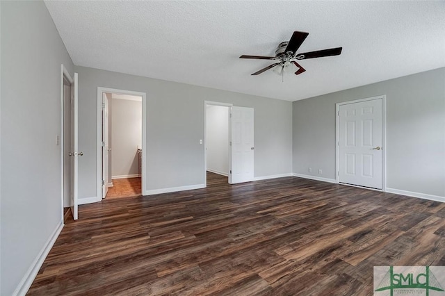 interior space featuring baseboards, a textured ceiling, and dark wood-style floors