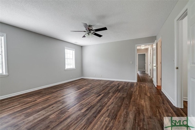 spare room featuring baseboards, ceiling fan, dark wood finished floors, and a textured ceiling