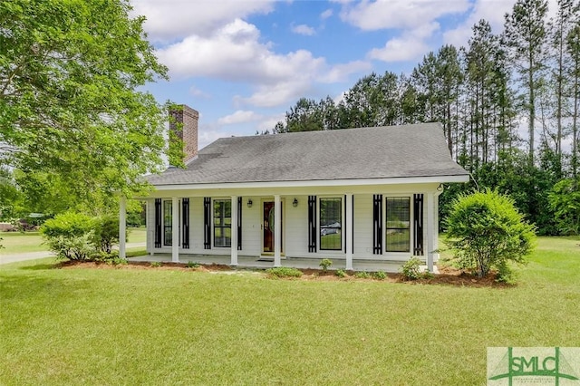view of front of house with a front lawn, covered porch, and a chimney