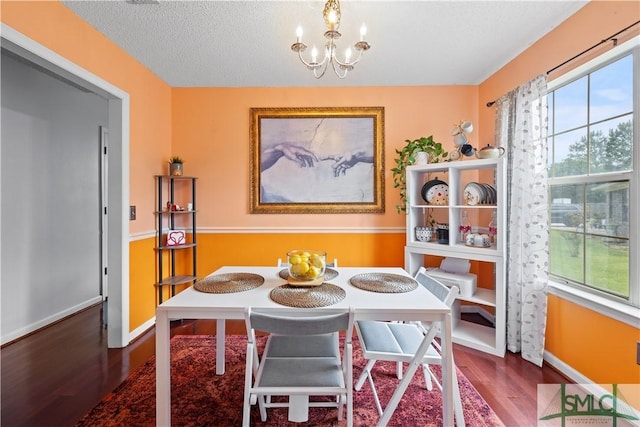 dining area with baseboards, a textured ceiling, wood finished floors, and a chandelier