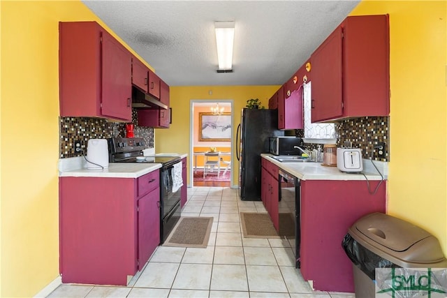 kitchen featuring red cabinetry, under cabinet range hood, and black appliances