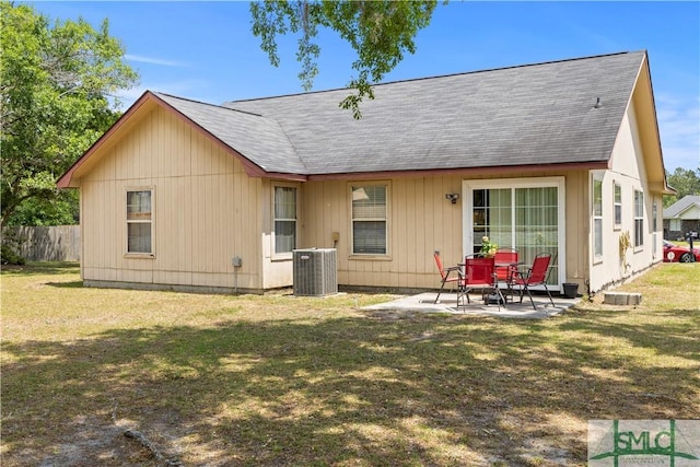 rear view of property featuring a lawn, fence, a shingled roof, and a patio area
