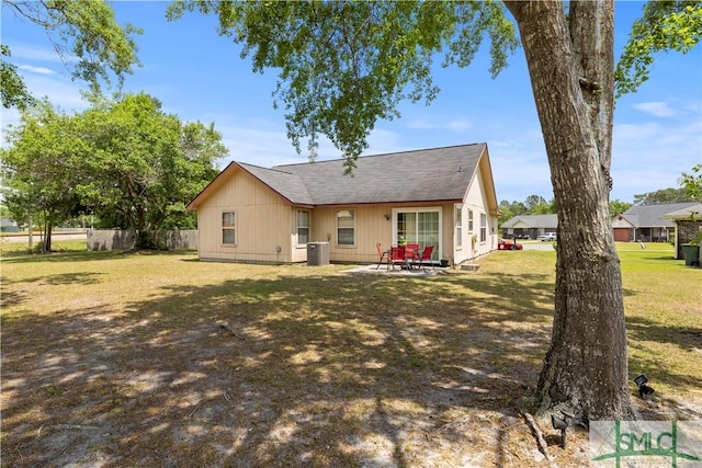 rear view of house with fence, cooling unit, a patio, roof with shingles, and a yard