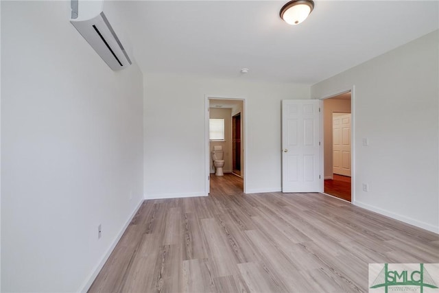 133 Ridgewood Cir, Rincon, GA 31326 - unfurnished bedroom featuring light wood-style floors, baseboards, a wall mounted AC, and connected bathroom