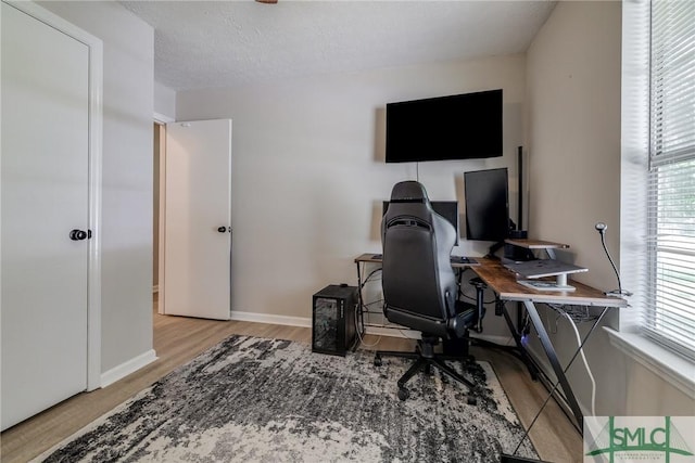 home office with baseboards, light wood-type flooring, and a wealth of natural light