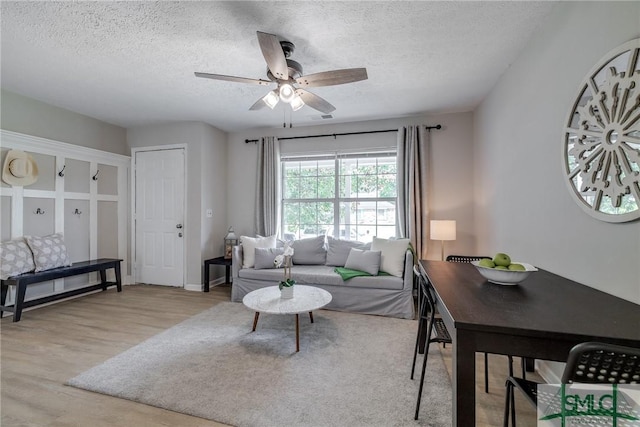 living area with light wood-type flooring, a textured ceiling, and ceiling fan