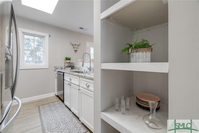 kitchen with a sink, white cabinets, stainless steel appliances, and a wealth of natural light