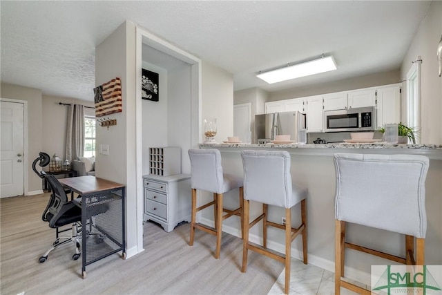 kitchen featuring light wood-style floors, light countertops, a breakfast bar, and stainless steel appliances