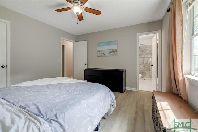 bedroom featuring ceiling fan, baseboards, light wood finished floors, and ensuite bath