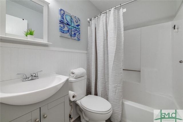 bathroom with toilet, shower / bath combination with curtain, wainscoting, and vanity