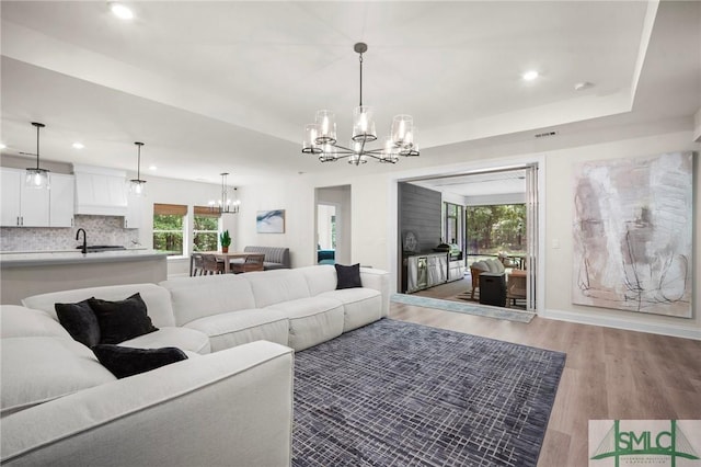 20 Serenity Pt, Savannah, GA 31419 - living area featuring a notable chandelier, recessed lighting, baseboards, light wood-type flooring, and a tray ceiling