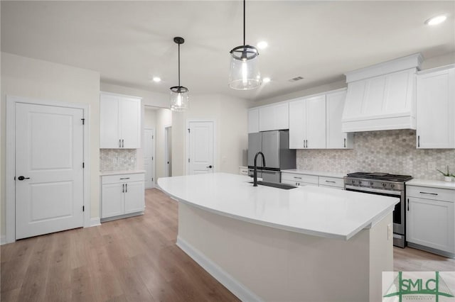 20 Serenity Pt, Savannah, GA 31419 - kitchen featuring appliances with stainless steel finishes, a sink, light wood finished floors, a kitchen island with sink, and decorative backsplash