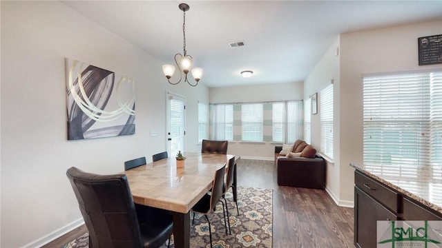 dining space with dark wood-type flooring, a chandelier, visible vents, and a wealth of natural light