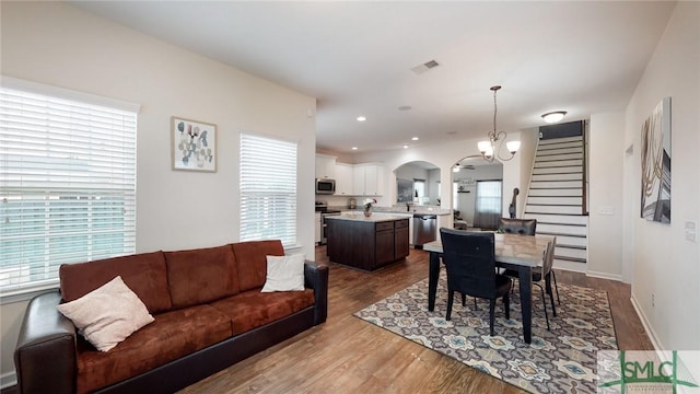 dining space featuring visible vents, stairs, baseboards, dark wood-type flooring, and arched walkways