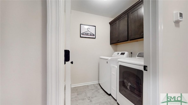 laundry room featuring washing machine and clothes dryer, baseboards, and cabinet space