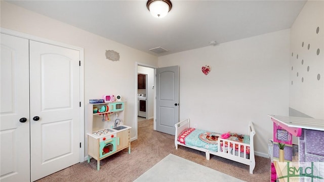 carpeted bedroom with a closet, washer / dryer, and baseboards